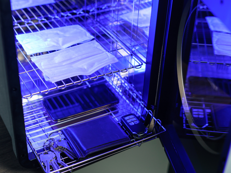 Face masks, wallet, and keys inside UV-C LED sterilization machine for personal item disinfection in Malaysia